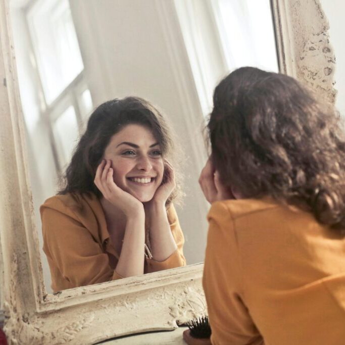 smiling woman looking at her self in the mirror